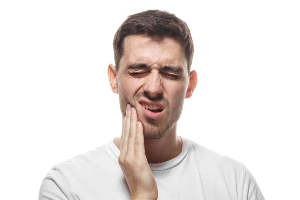 man holding his jaw, indicating severe tooth pain, likely in need of root canal therapy